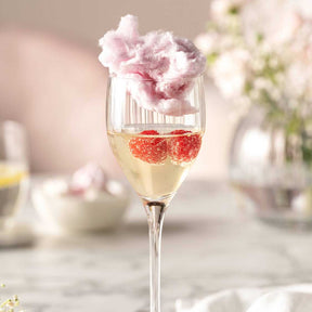 Likörglas POESIA mit Champagner, Himbeeren und rosa Zuckerwatte, dekorativ gedeckter Tisch