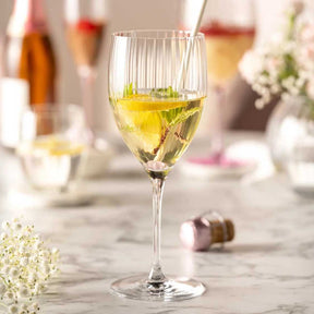 Weinglas mit gelblichem Getränk auf gedecktem Tisch mit Blumendeko