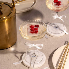 Champagnerschalen POESIA mit roten Beeren auf gedecktem Tisch mit Besteck und Weinflasche