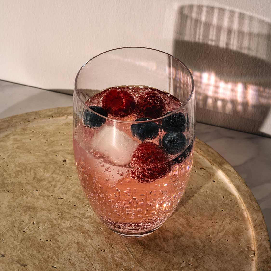 Trinkglas POESIA mit Beeren und Eis auf Untersetzer, Sonnenlicht
