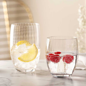 Zwei gefüllte Trinkgläser POESIA mit Zitrone und Himbeeren auf Marmortisch