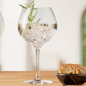 Gingläser mit Eiswürfeln, Rosmarinzweig und Brot auf Holztisch