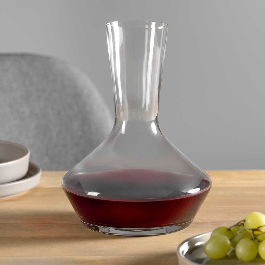 Dekanter PUCCINI mit Rotwein gefüllt auf Holztisch, Trauben und Schalen sichtbar