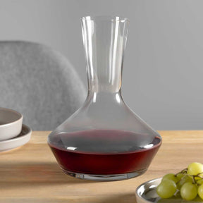 Dekanter PUCCINI mit Rotwein gefüllt auf Holztisch, Trauben und Schalen sichtbar