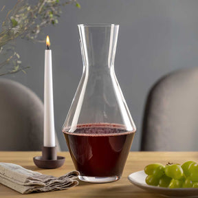 Weinset PUCCINI mit gefüllter Karaffe auf gedecktem Tisch, Kerze und Trauben