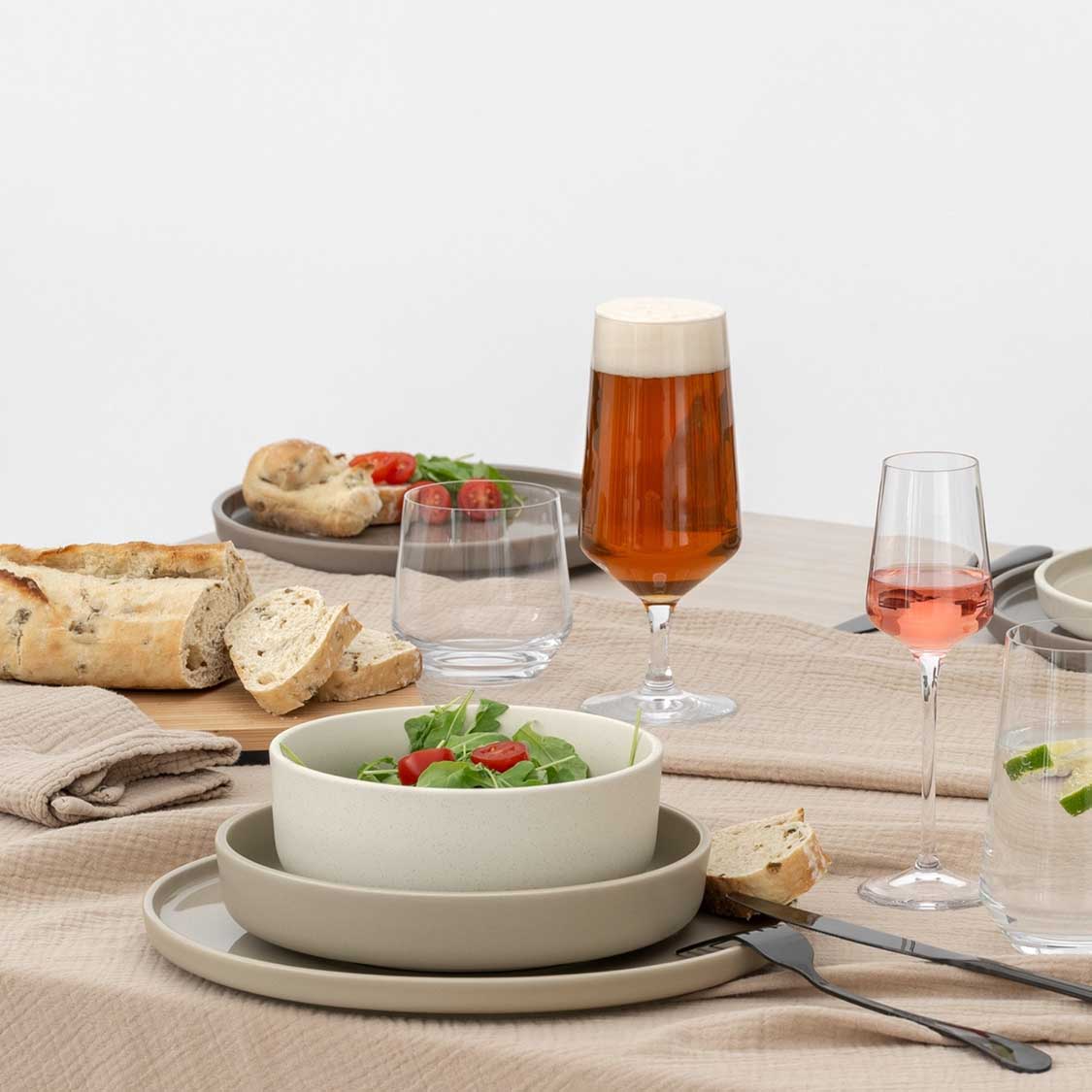 Gedeckter Tisch mit Biergläsern, Brot, Salat und Getränken