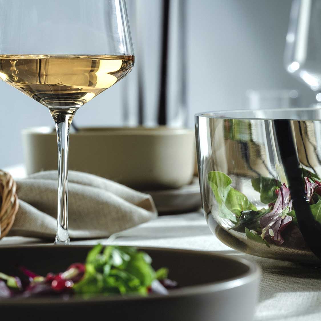 Weißweinglas PUCCINI mit Weißwein gefüllt auf gedecktem Tisch mit Geschirr und Kräutern