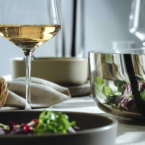 Weißweinglas PUCCINI mit Weißwein gefüllt auf gedecktem Tisch mit Geschirr und Kräutern