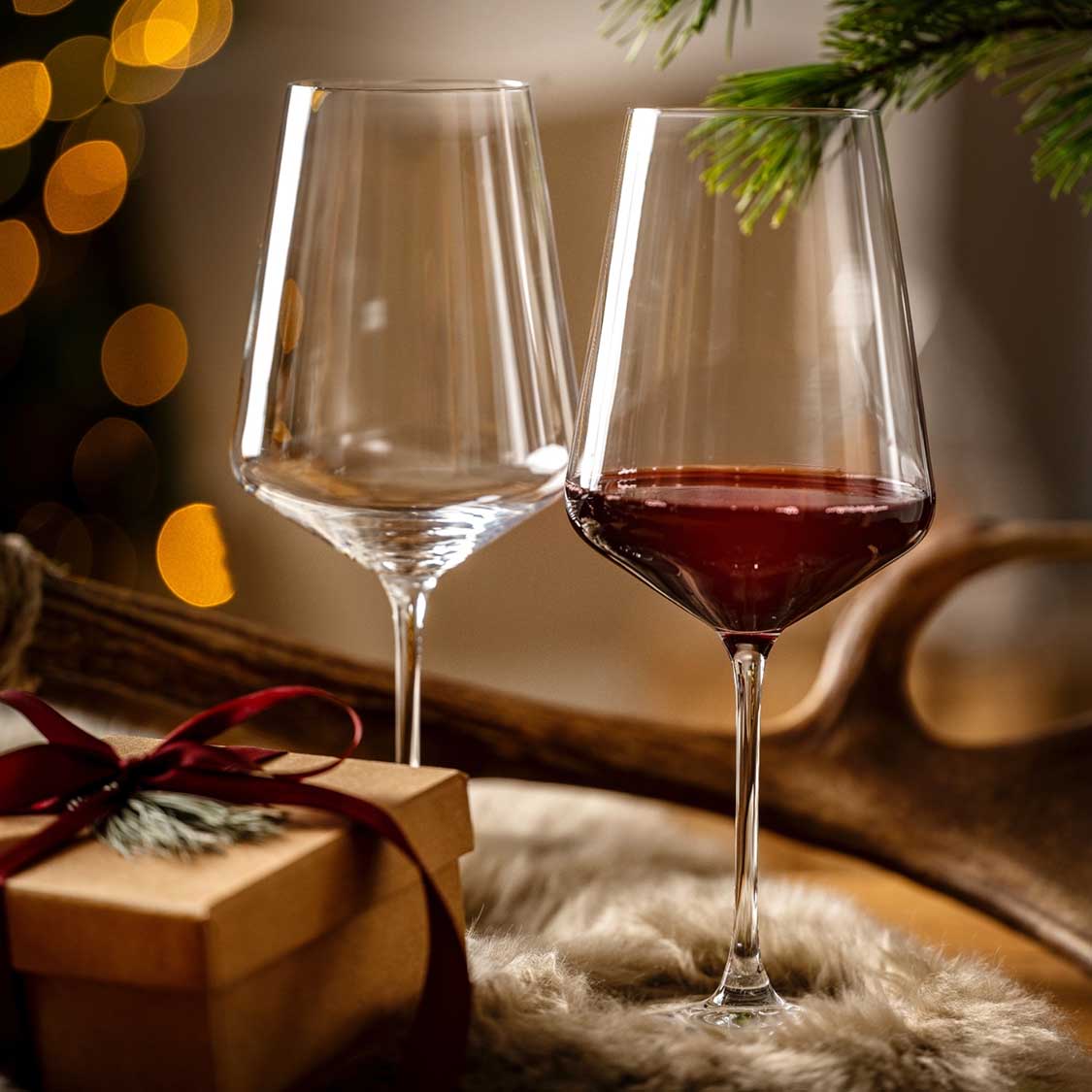 Rotweinglas PUCCINI mit Rotwein gefüllt neben leerem Glas in festlicher Weihnachtsdeko