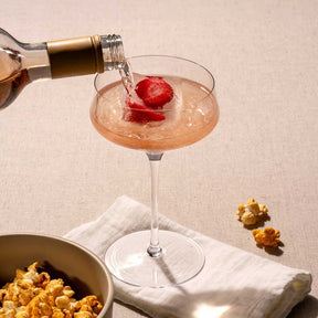 Champagnerschale PUCCINI wird gefüllt, mit Erdbeere und Eiswürfeln, neben Popcorn und Serviette