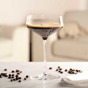 Champagnerschale PUCCINI mit Kaffeelikör gefüllt, daneben Kaffeebohnen auf weißer Oberfläche