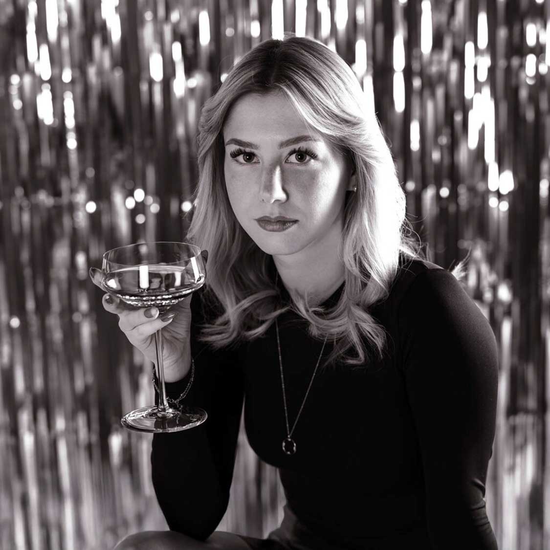 Frau mit Champagnerschale PUCCINI vor glitzerndem Hintergrund