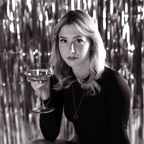 Frau mit Champagnerschale PUCCINI vor glitzerndem Hintergrund