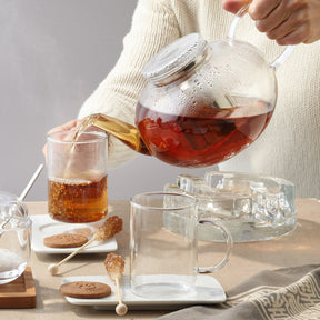Teekanne MOON wird über Tasse mit Tee eingegossen, gedeckter Tisch mit Gebäck