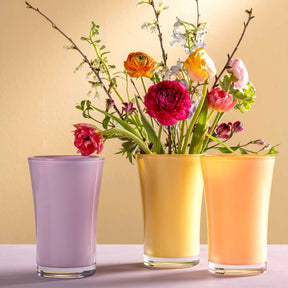 Drei Glasvasen mit Blumenstrauss auf hellem Hintergrund, lila Vase links