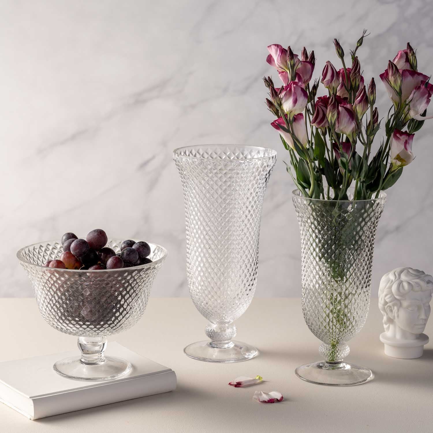 Vase auf Fuß POESIA mit rosa Blumen, daneben Obstschale und Deko auf Marmortisch