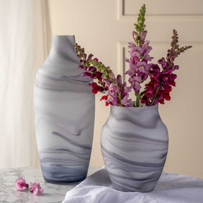 Zwei Vasen POESIA mit Marmoroptik, eine mit Blumenstrauss gefuellt, auf Marmortisch