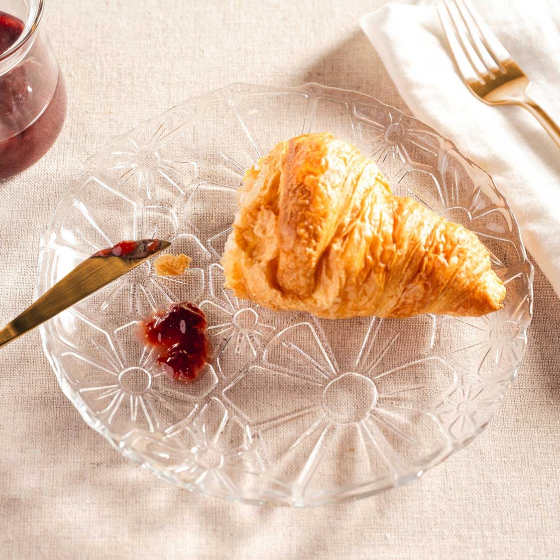 Teller GIORNO mit Croissant, Besteck und Rotwein auf gedecktem Tisch