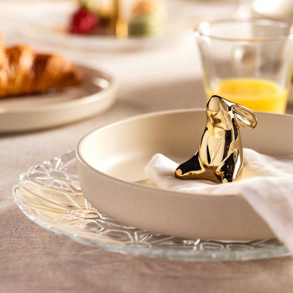 Teller GIORNO 27 cm mit goldener Dekofigur auf gedecktem Frühstückstisch