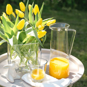 Krug GIORNO mit Orangensaft auf Tisch neben Tulpen