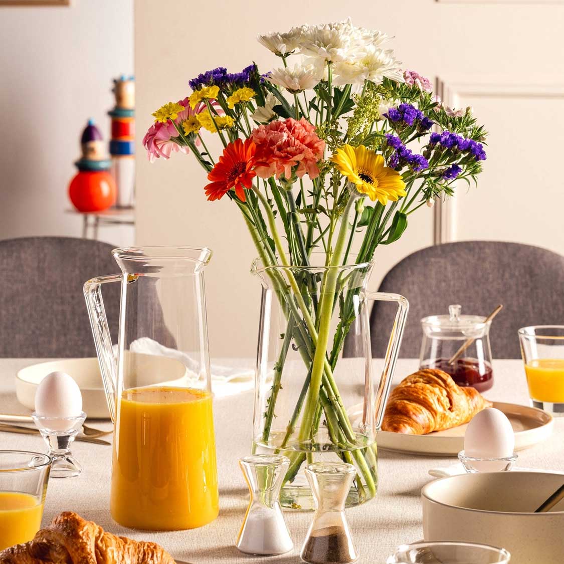 Krug GIORNO mit Blumenstrauß auf gedecktem Frühstückstisch