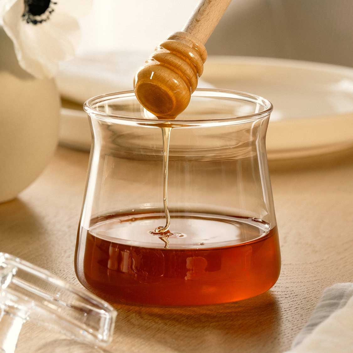 Dose GIORNO mit Honig und Honigstab auf Holztisch