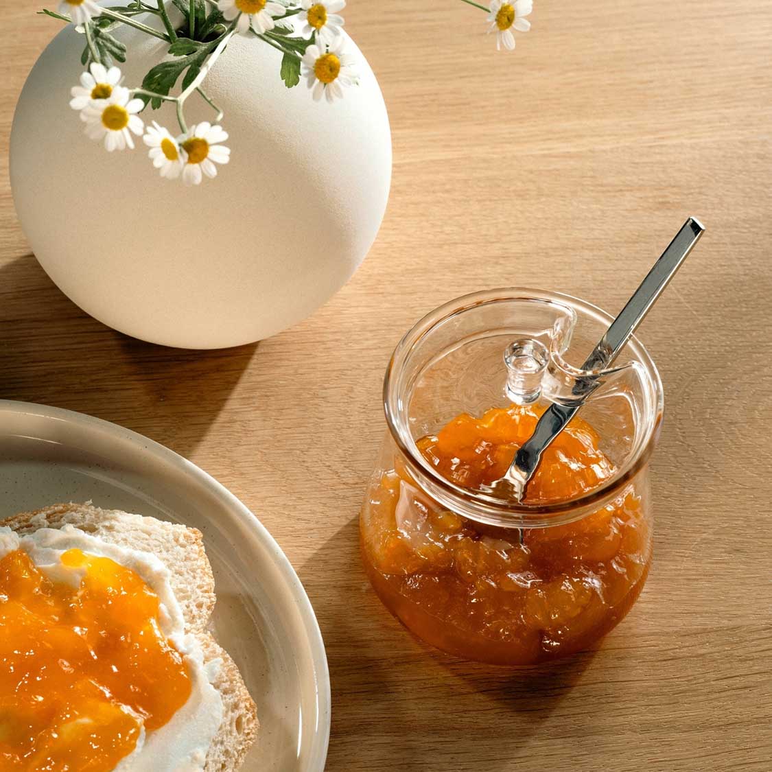 Dose GIORNO mit Marmelade gefüllt auf Holztisch, daneben Brot mit Aufstrich