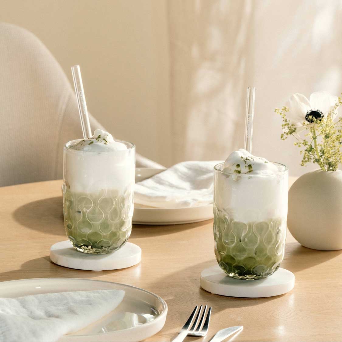 Matcha Latte Gläser GOCCE mit Glastrinkhalm auf gedecktem Tisch