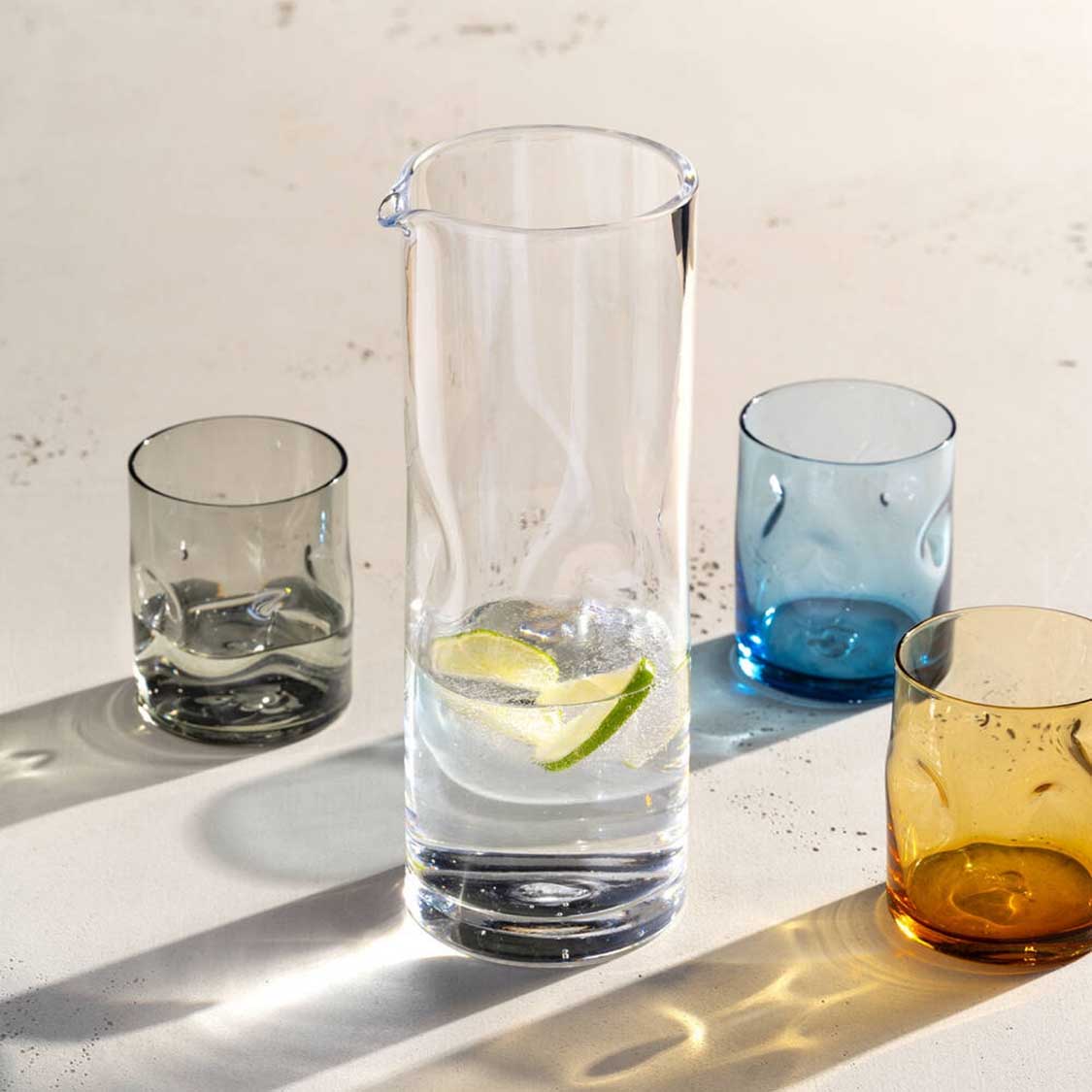Verschiedenfarbige Trinkgläser mit Getränken auf weißer Oberfläche