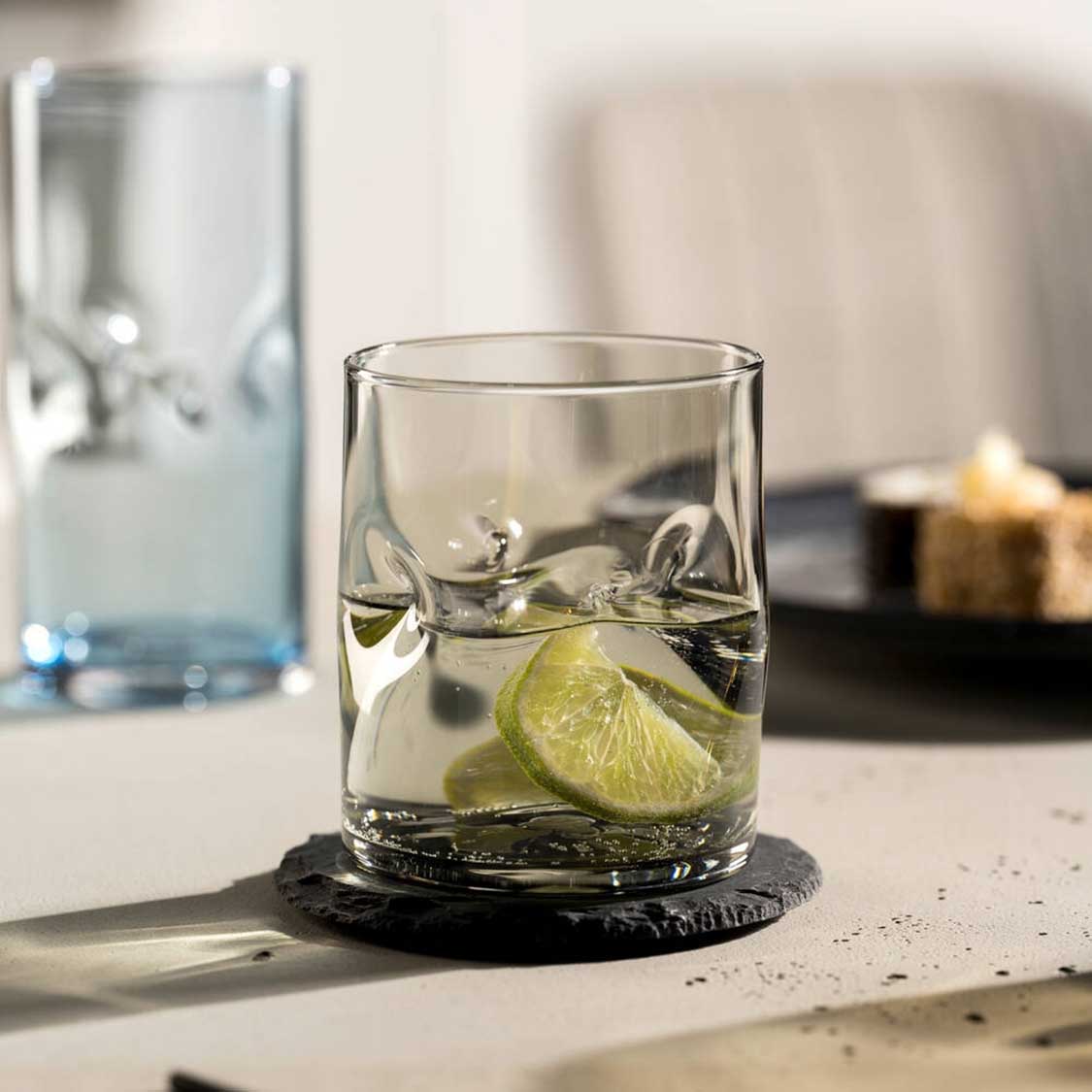 Trinkglas VESUVIO mit Limettenscheiben und Eis auf schwarzem Untersetzer