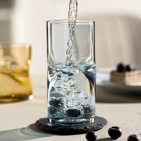 Wasser wird in Trinkglas VESUVIO eingegossen, Blaubeeren daneben