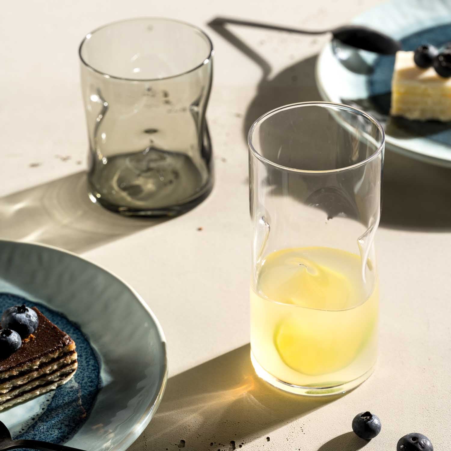 Trinkglas VESUVIO mit Zitronensaft auf gedecktem Tisch mit Dessert