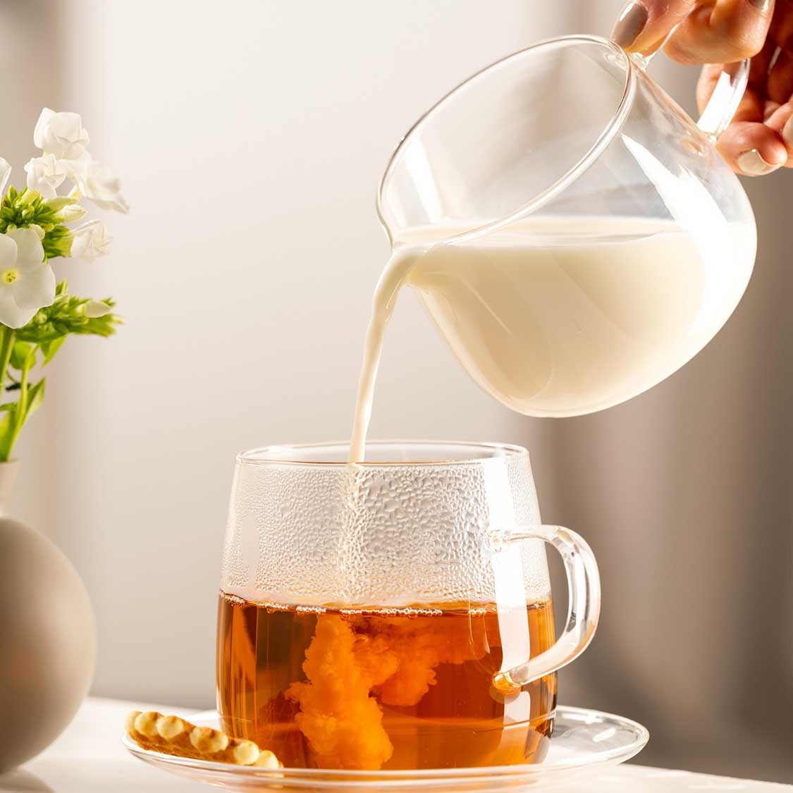 Milchkännchen TÈ PER TE gießt Milch in Teetasse mit Tee