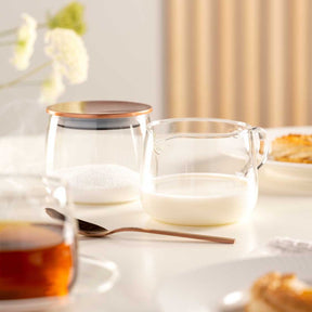 Milchkännchen TÈ PER TE auf gedecktem Tisch mit Tasse und Gebäck