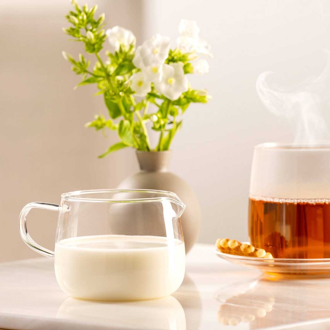 Milchkännchen TÈ PER TE auf Tisch mit Tee und Blumen