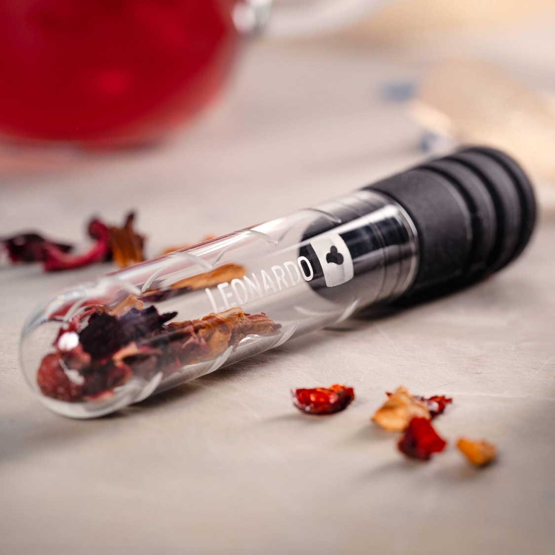 Teeinfuser TÈ PER TE mit getrockneten Blüten und Kräutern auf grauer Oberfläche