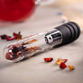 Teeinfuser TÈ PER TE mit getrockneten Blüten und Kräutern auf grauer Oberfläche