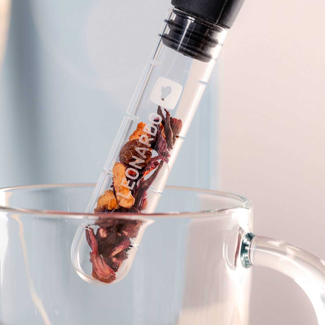 Teeinfuser TÈ PER TE in Glas über Tasse mit Teeblättern
