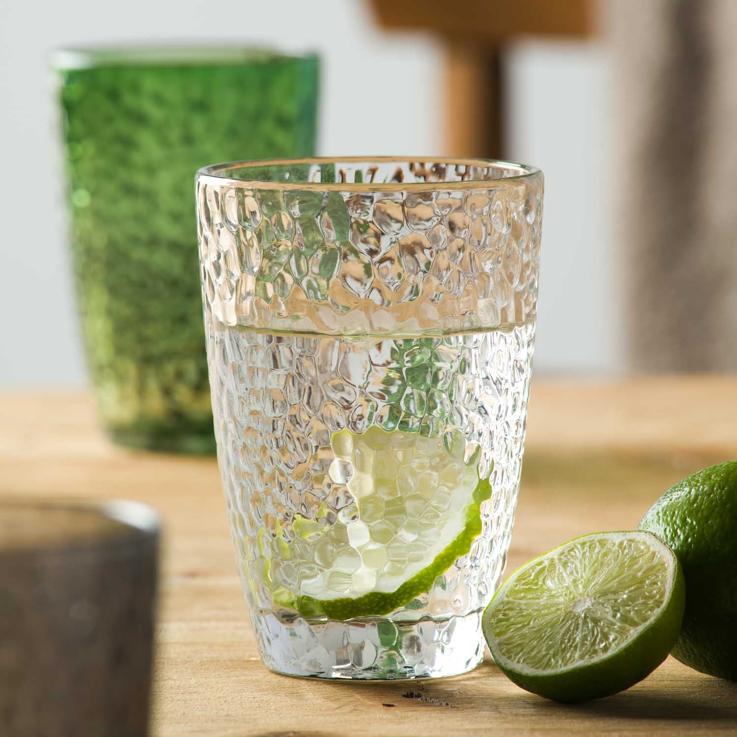 Trinkglas MATERA mit Limettenscheibe und Wasser auf Holzfläche