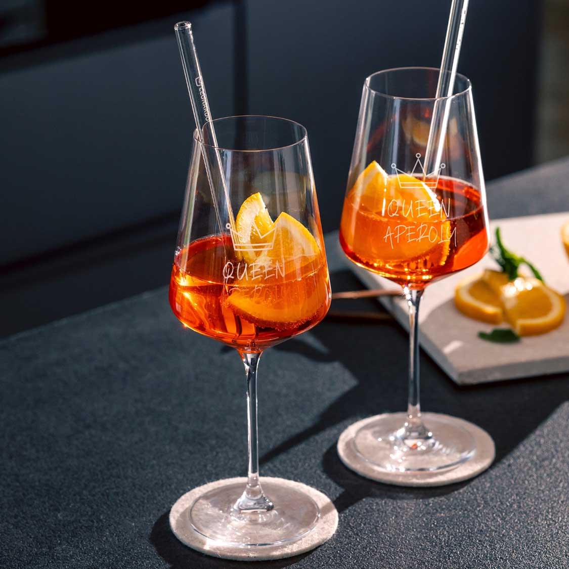 Zwei Weißweingläser PUCCINI mit Aperitif-Getränk, Eiswürfeln und Glasstrohhalmen auf gedecktem Tisch