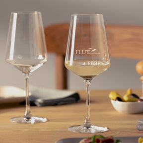 Zwei Rotweingläser PUCCINI mit Ebbe/Flut Gravur auf Holztisch, eines gefüllt mit Weißwein