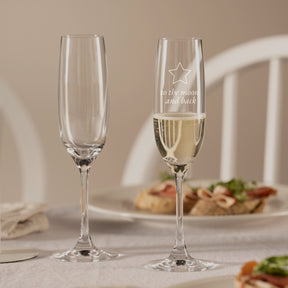 Zwei Sektgläser CIAO+ auf gedecktem Tisch, eines mit Gravur gefüllt mit Sekt
