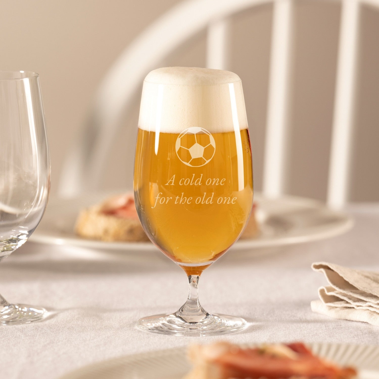Bierglas CIAO+ mit Gravur, gefüllt mit Bier, auf gedecktem Tisch