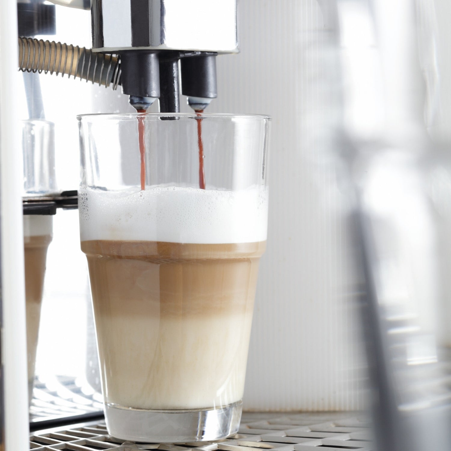 Becher SOLO mit Cappuccino unter Espressomaschine, Milchschaum oben