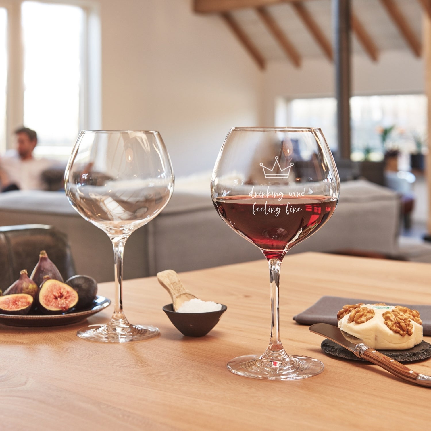 Burgundergläser CIAO+ mit Gravur auf gedecktem Tisch, gefüllt mit Wein und Wasser, neben Feigen und Gebäck