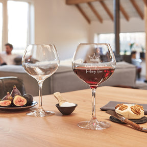 Burgundergläser CIAO+ mit Gravur auf gedecktem Tisch, gefüllt mit Wein und Wasser, neben Feigen und Gebäck