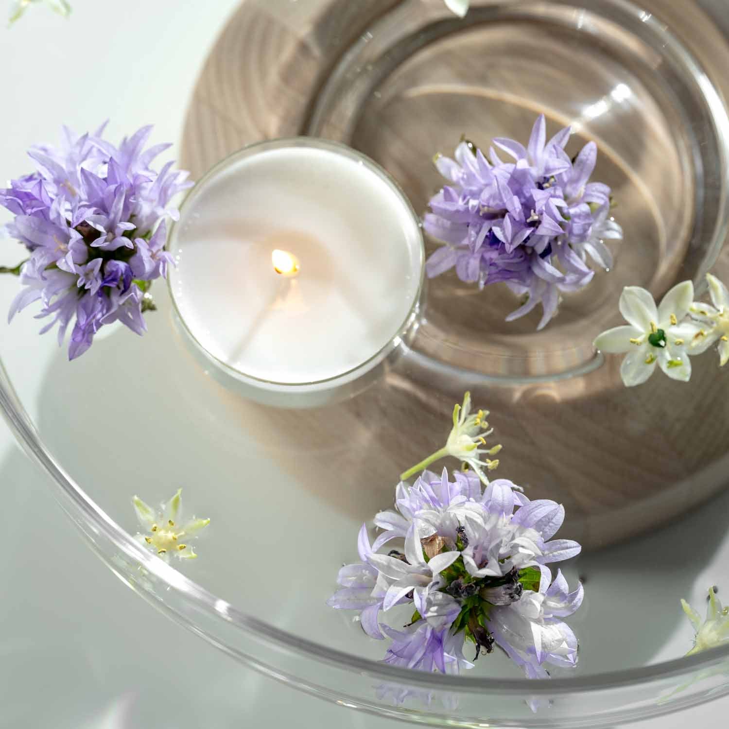 Glasschale mit Kerze und lila Blüten dekoriert, Draufsicht