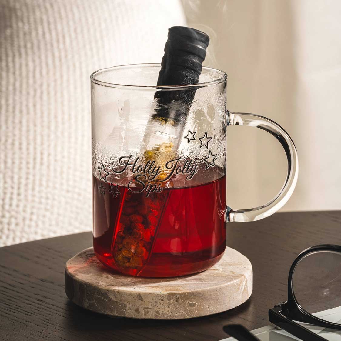 Teeglas NOVO mit rotem Tee, Infuser und Holzuntersetzer auf Tisch