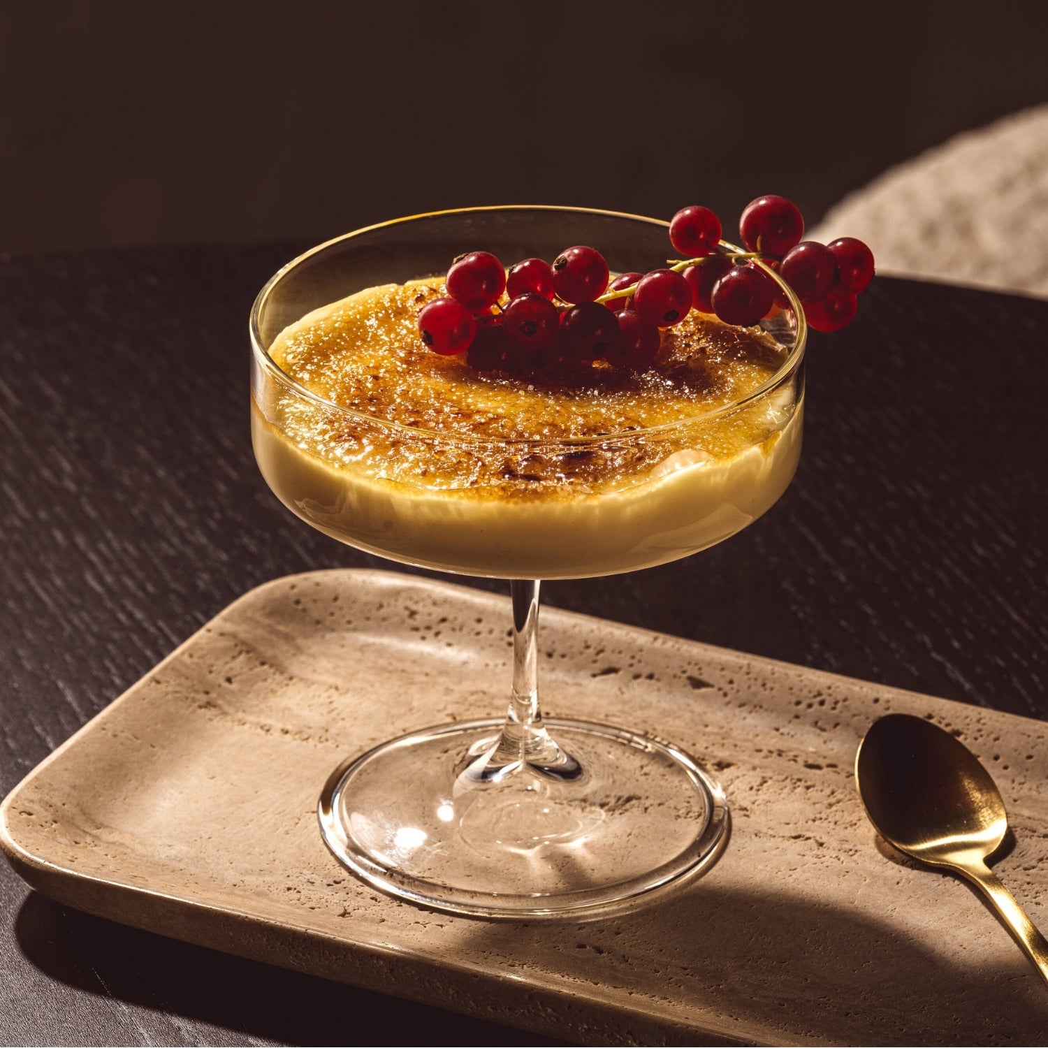 Creme Brulee angerichtet mit einem Zweig Johanissbeeren in der BASSO Schale
