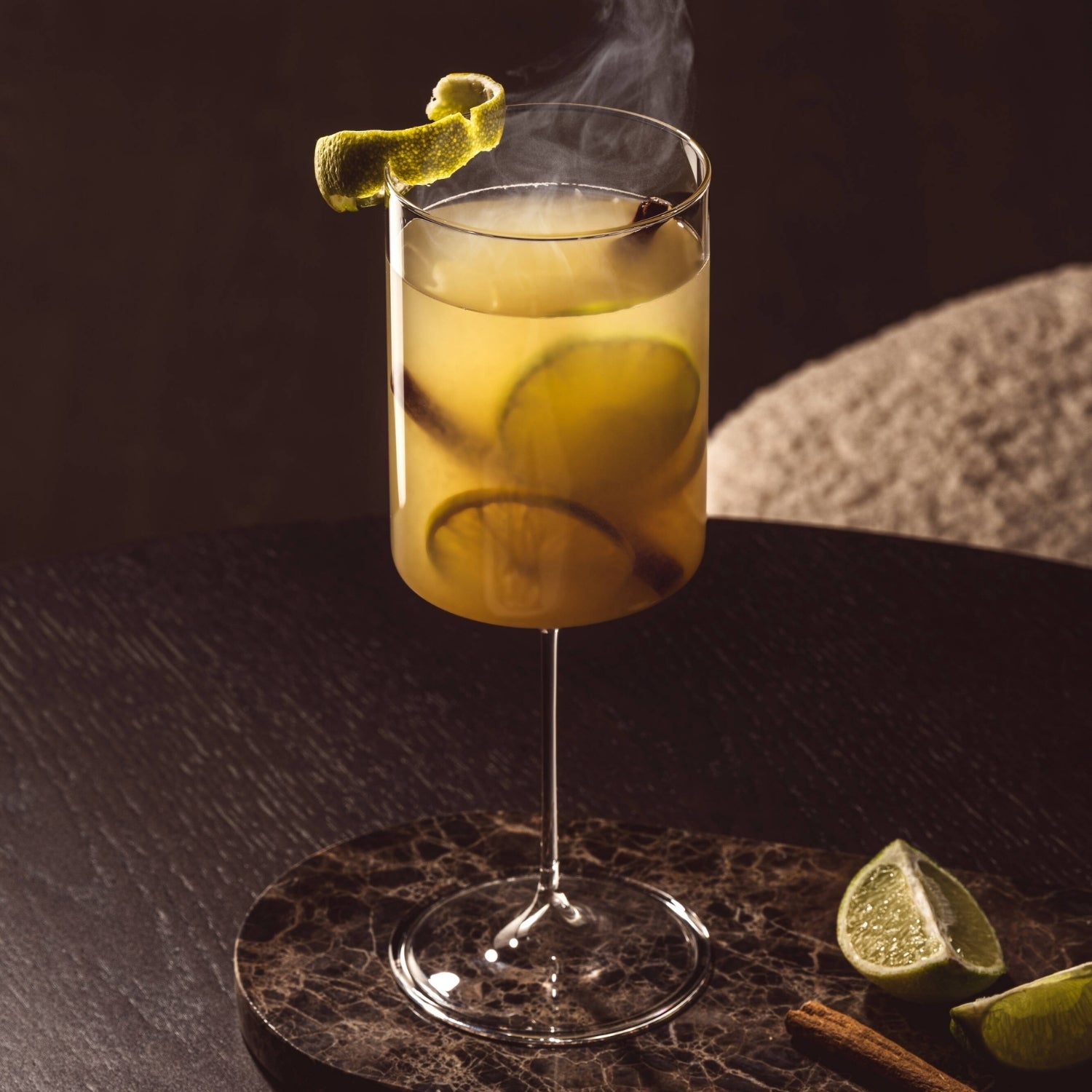 Hot Caipirinha dampft im BASSO Kelch, dekoriert mit einer Limettenzeste am Glasrand